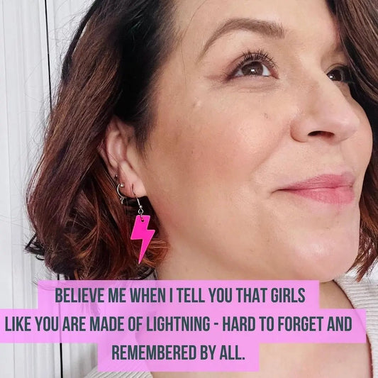 a woman smiling with a pink lightning bolt earring