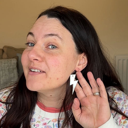 a woman holding a lightning bolt earring