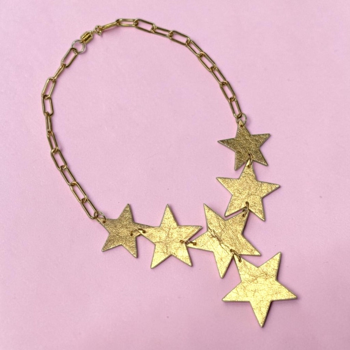 a gold star necklace on a pink background