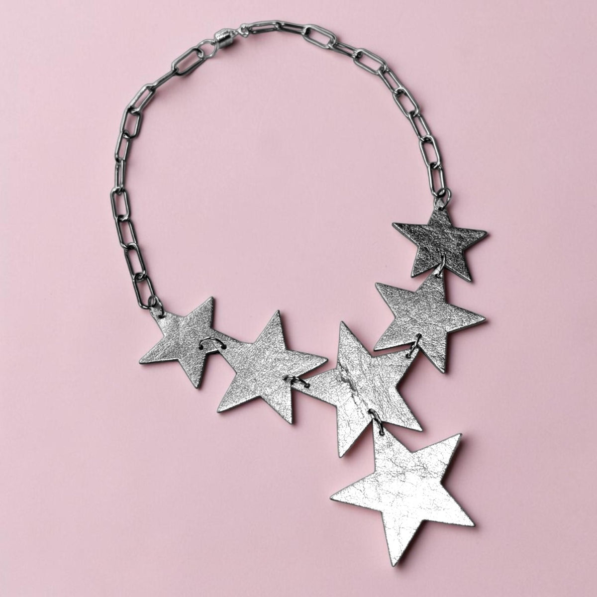 a silver star necklace on a pink background