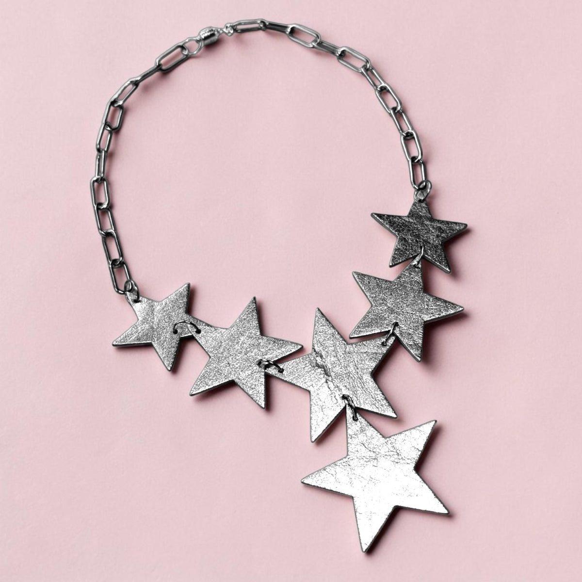 a silver star necklace on a pink background