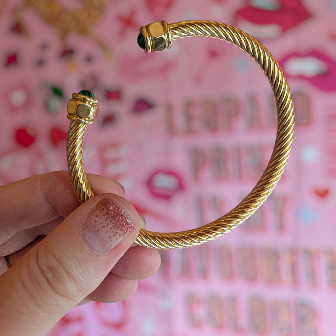 a hand holding a gold bracelet