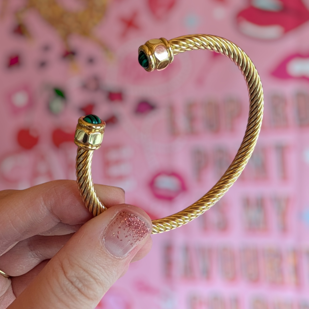 a hand holding a gold bracelet
