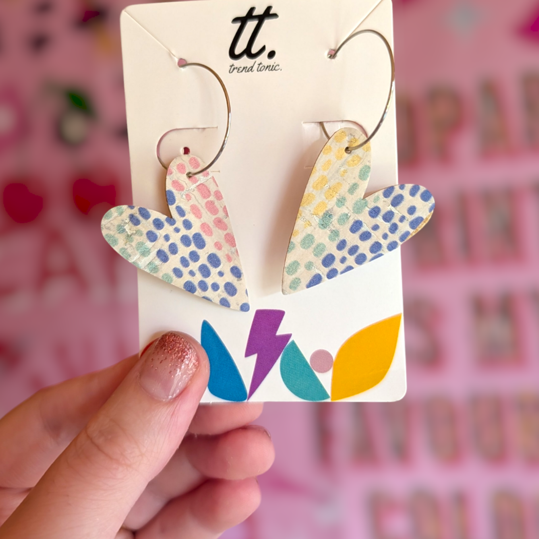 a hand holding a pair of heart shaped earrings