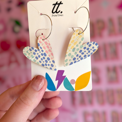 a hand holding a pair of heart shaped earrings
