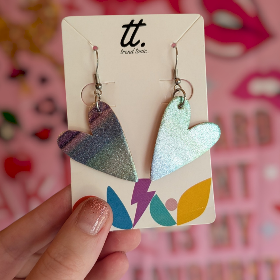 a hand holding a pair of heart shaped earrings