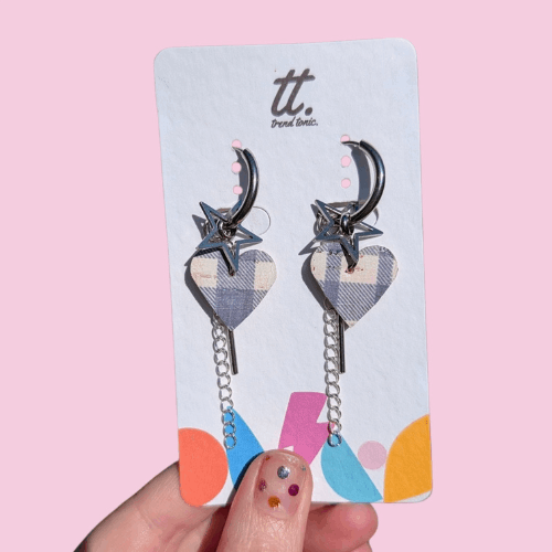 a hand holding a pair of heart earrings
