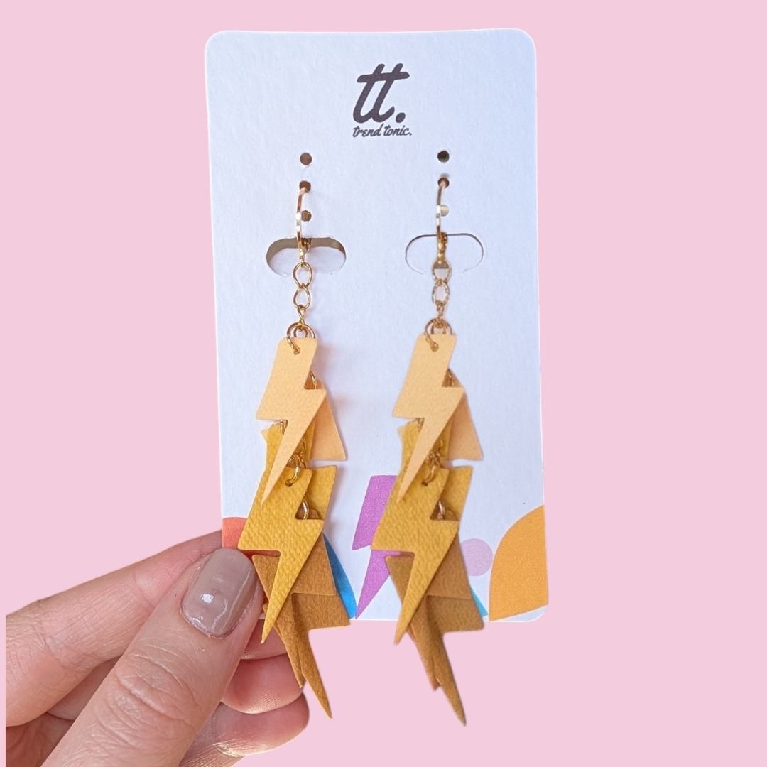 a hand holding a pair of lightning bolt earrings