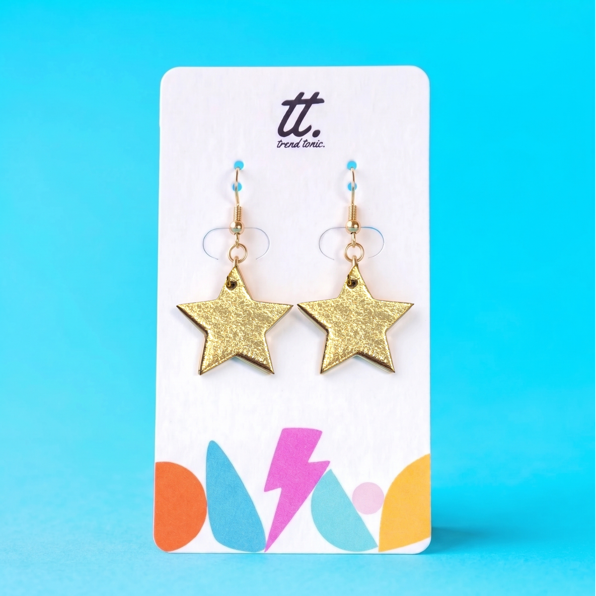 a pair of gold star earrings on a white card