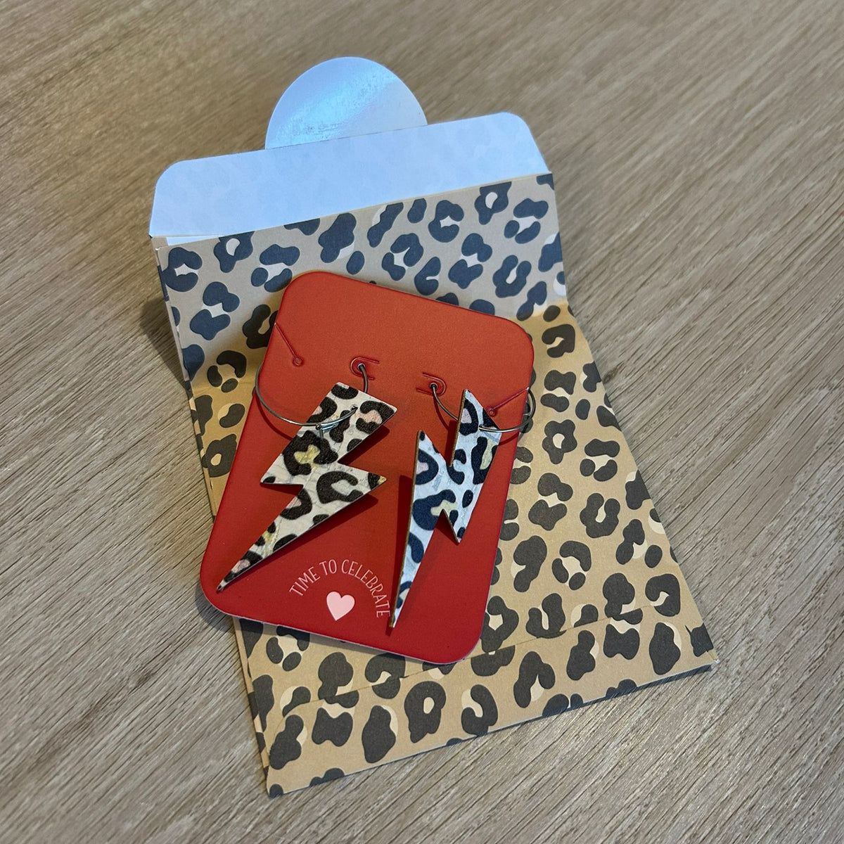 a red and black earrings on a cheetah print envelope