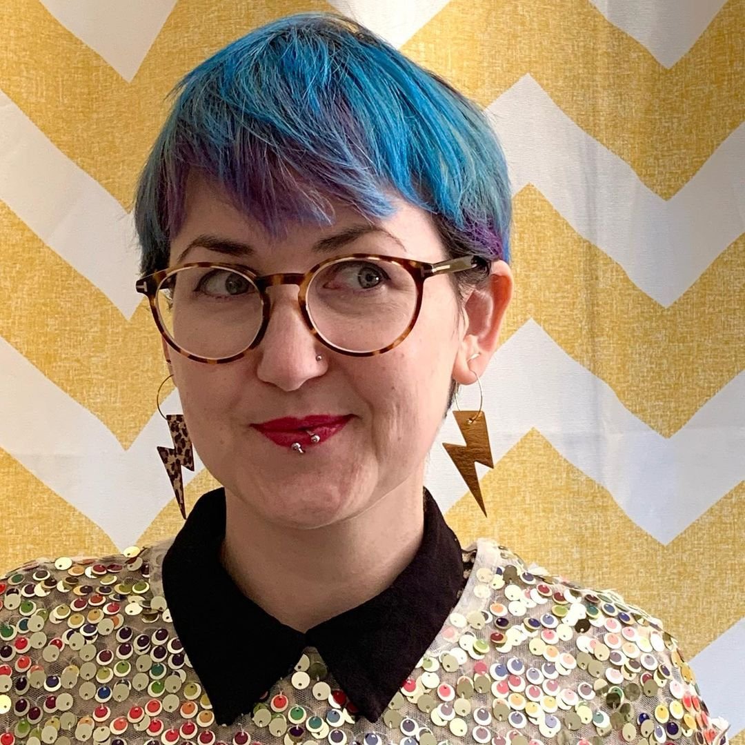 a woman with blue hair and glasses