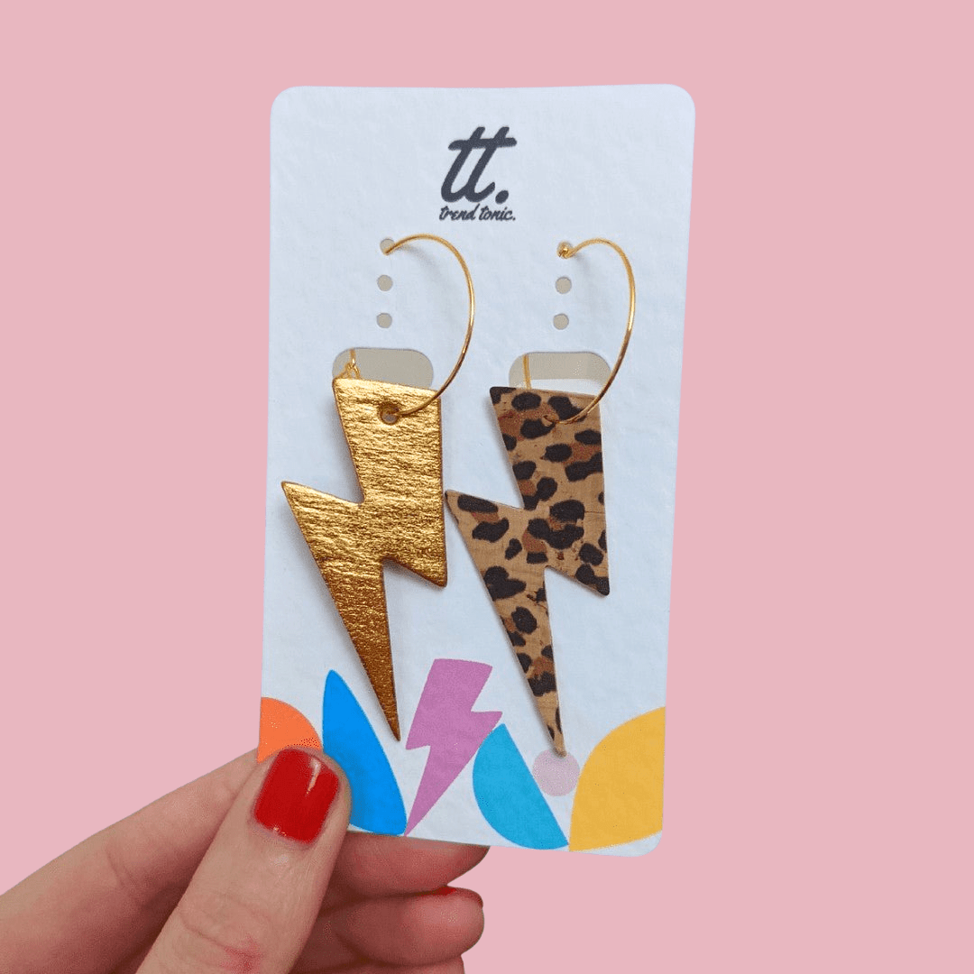a hand holding a card with lightning bolts earrings