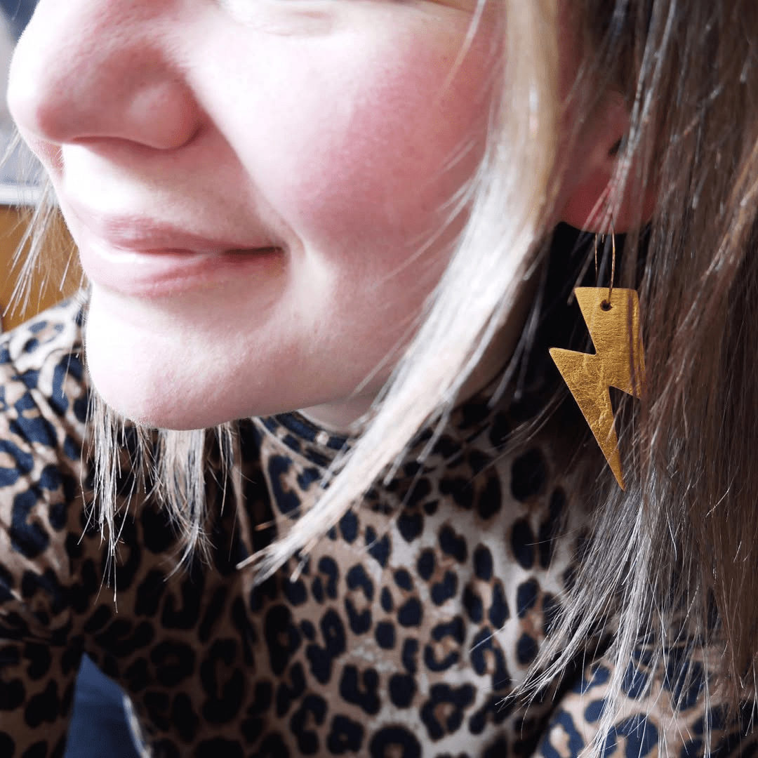 a woman wearing a leopard print shirt and a lightning bolt earring