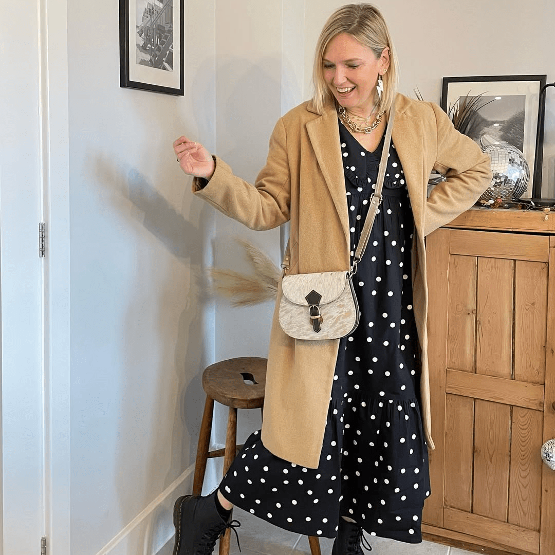 a woman in a polka dot dress and a tan coat