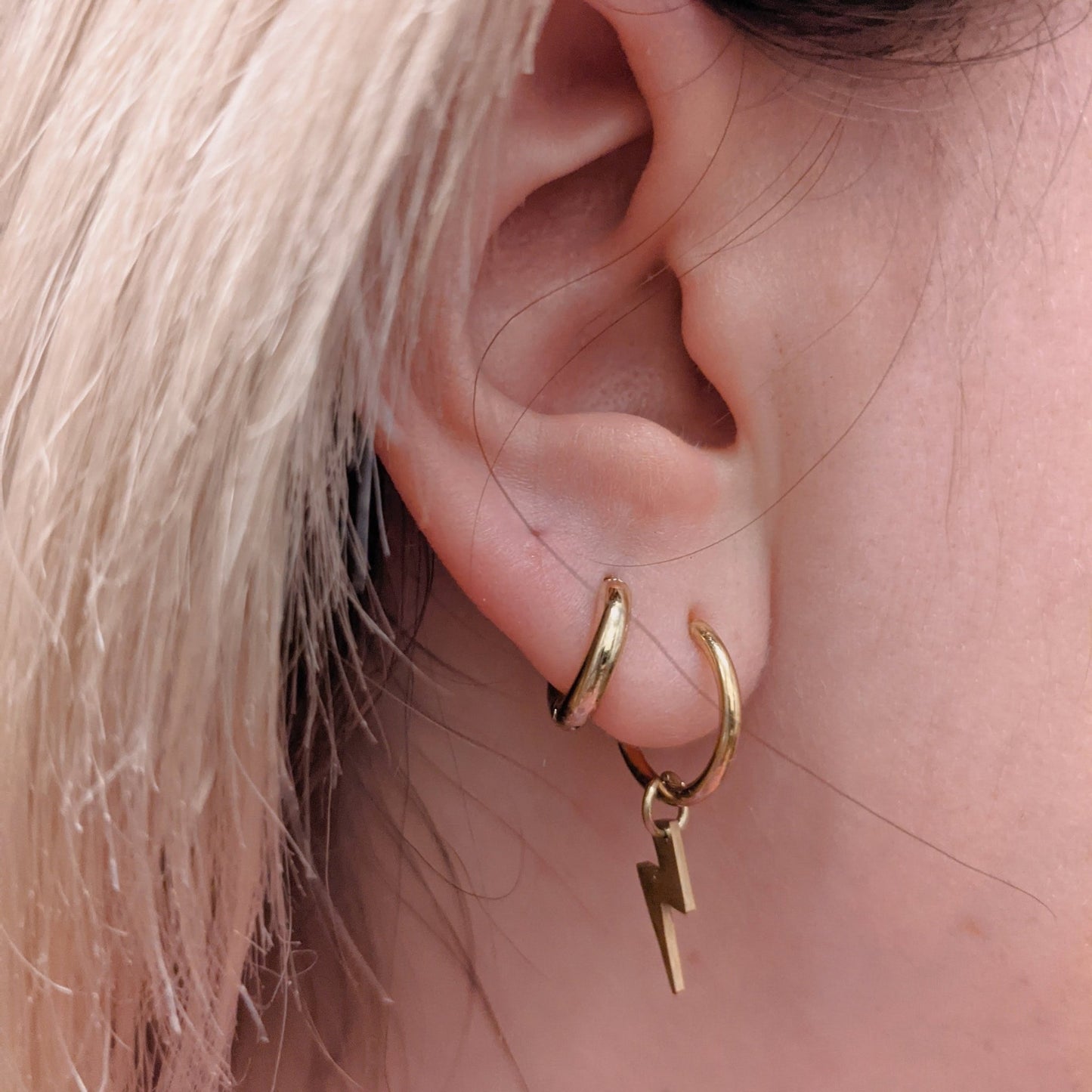 a close up of a woman's ear with gold hoops