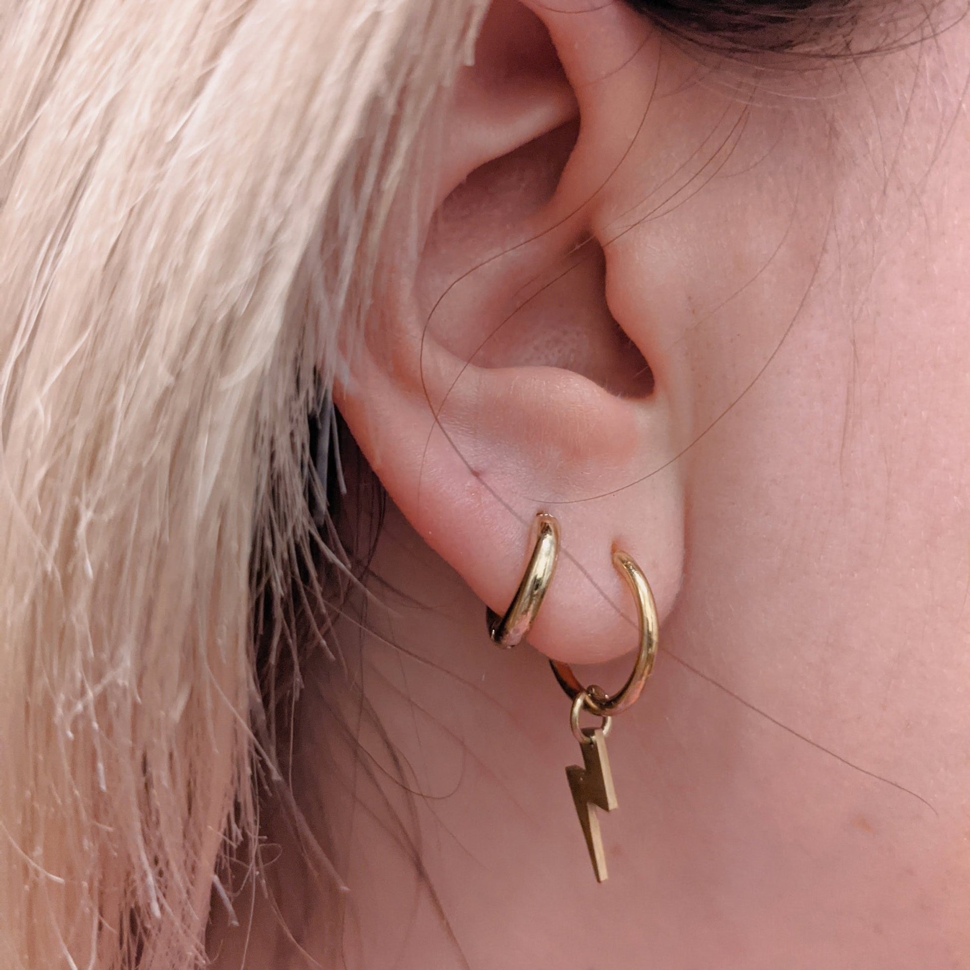 a close up of a woman's ear with gold hoops