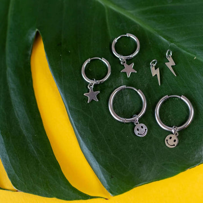 a group of silver earrings on a leaf
