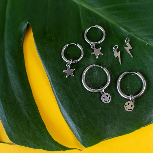 a group of silver earrings on a leaf