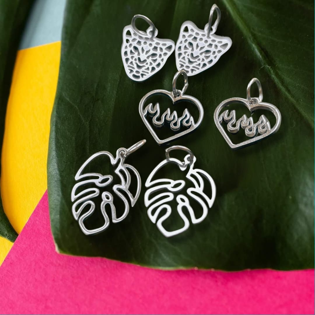 a group of silver earrings on a leaf