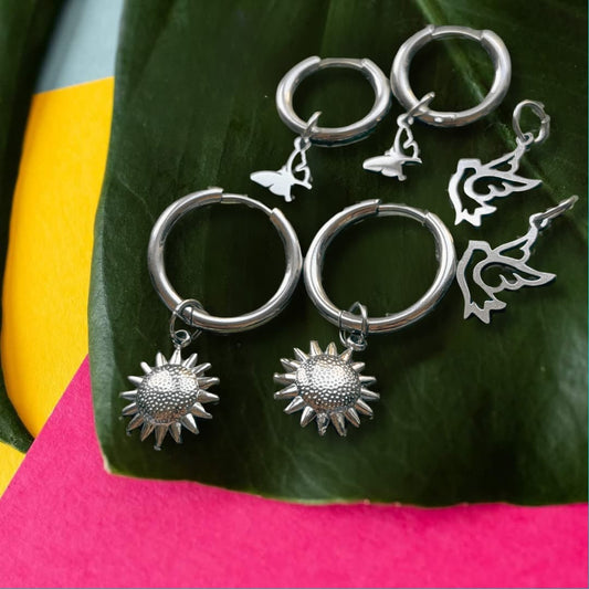 a group of silver earrings on a leaf