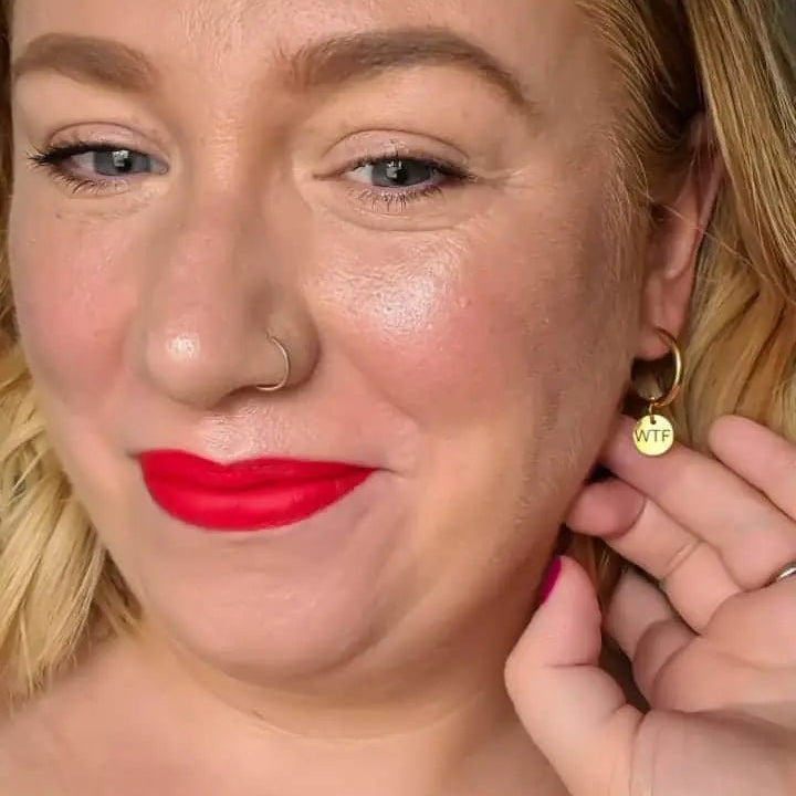 a woman with red lipstick and earrings