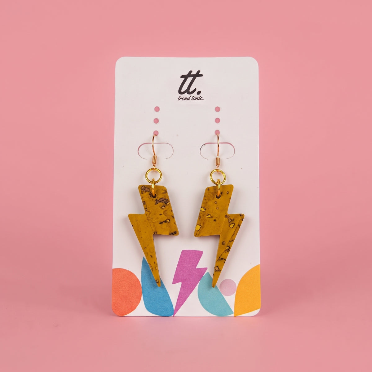 A pair of yellow-tone lightning bolt drop earrings with a textured mustard-yellow finish, displayed on a white card from the brand 'tt. Design Co.
