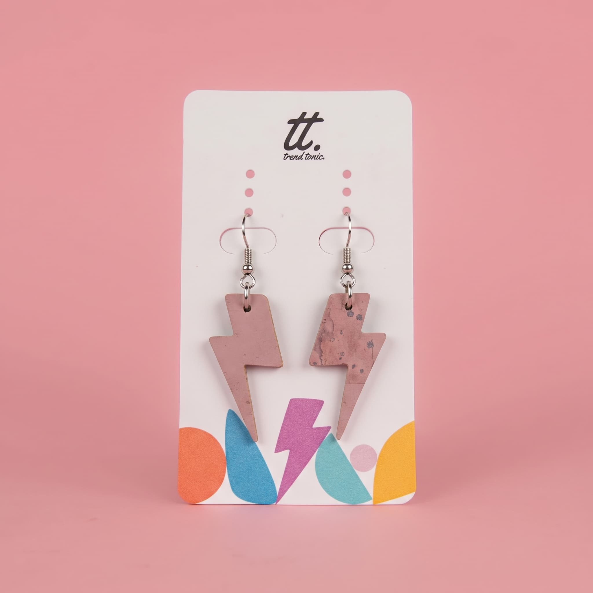 A pair of lightning bolt drop earrings in a pink marbled finish, displayed on a white brand card with the logo 'tt. Paint Colors' against a solid pink background.
