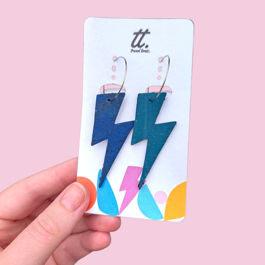 a hand holding a card with lightning bolts earrings