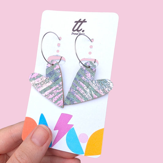 a hand holding a pair of heart shaped earrings