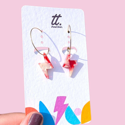 a hand holding a pair of earrings