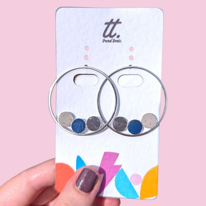 a hand holding a card with silver hoops