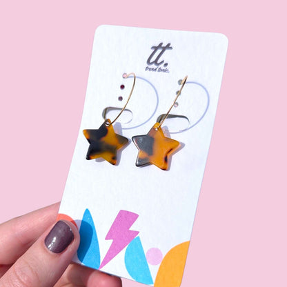 a hand holding a card with earrings