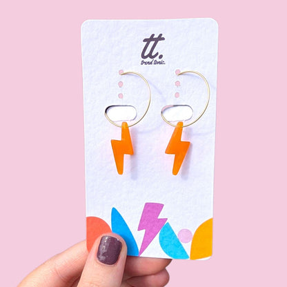 a hand holding a pair of lightning bolt earrings