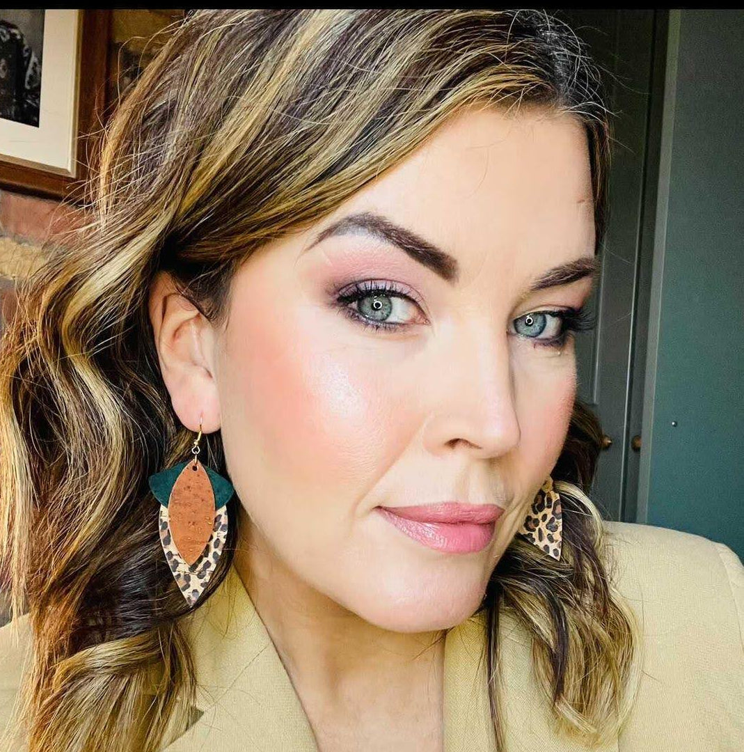 a woman with blue eyes and brown hair wearing earrings