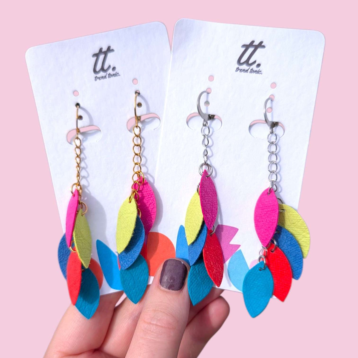 a hand holding earrings with colorful leaves