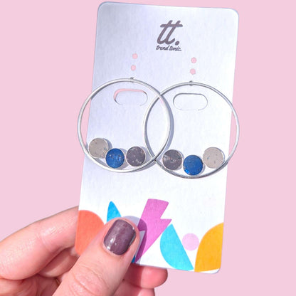 a hand holding a card with silver hoops