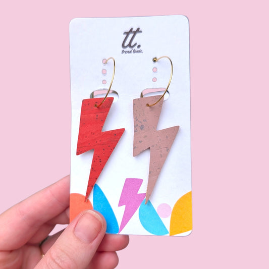a hand holding a card with lightning bolts earrings
