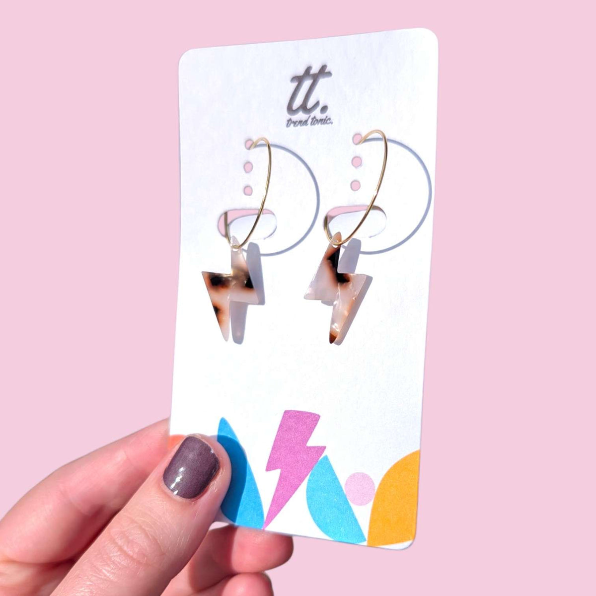 a hand holding a card with earrings