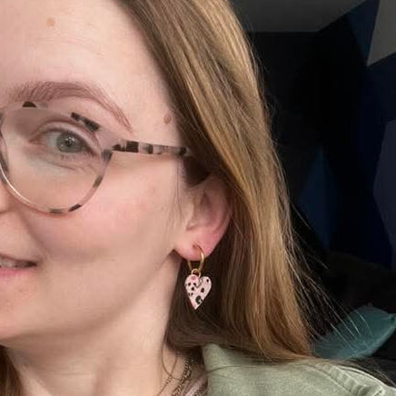 a woman wearing glasses and a heart shaped earrings