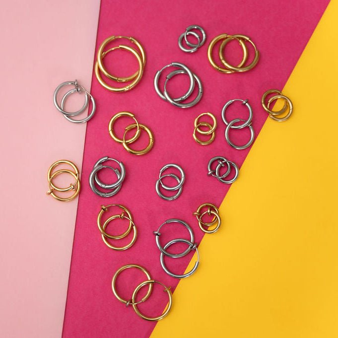 a group of silver and gold hoops on a pink and yellow background